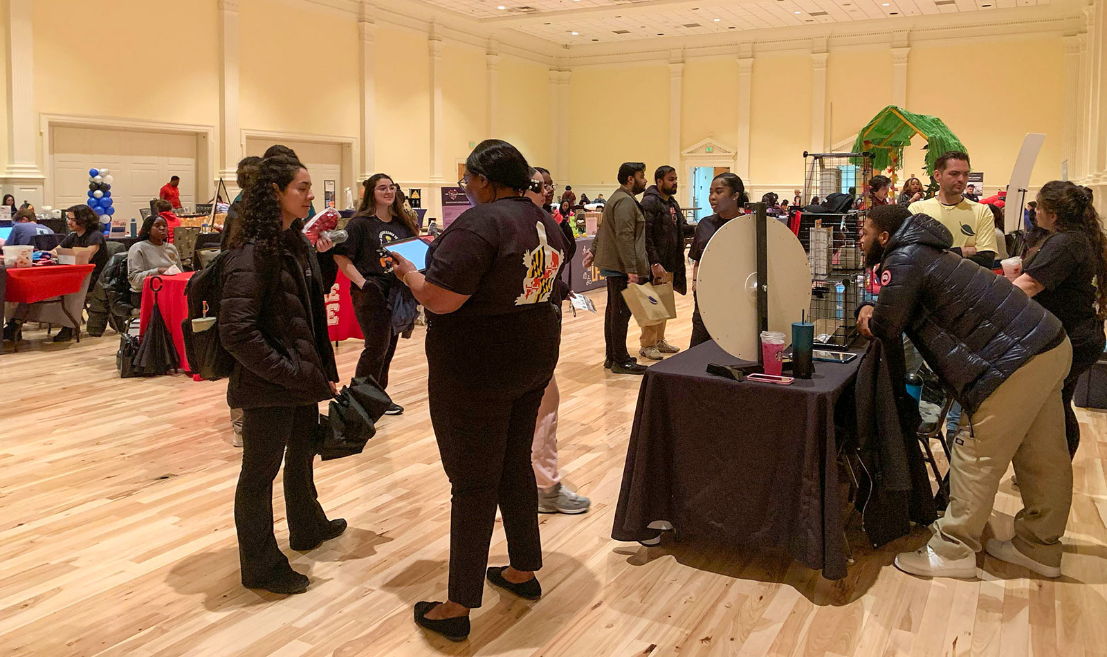 Students speaking with representatives of an off campus property in a ballroom space during the living fair.